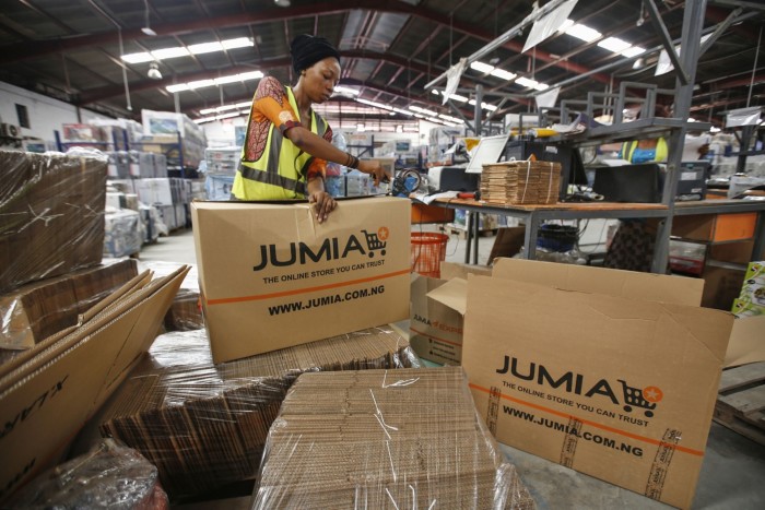 A worker packs goods inside branded cardboard boxes at a Jumia Technologies distribution warehouse in Lagos, Nigeria