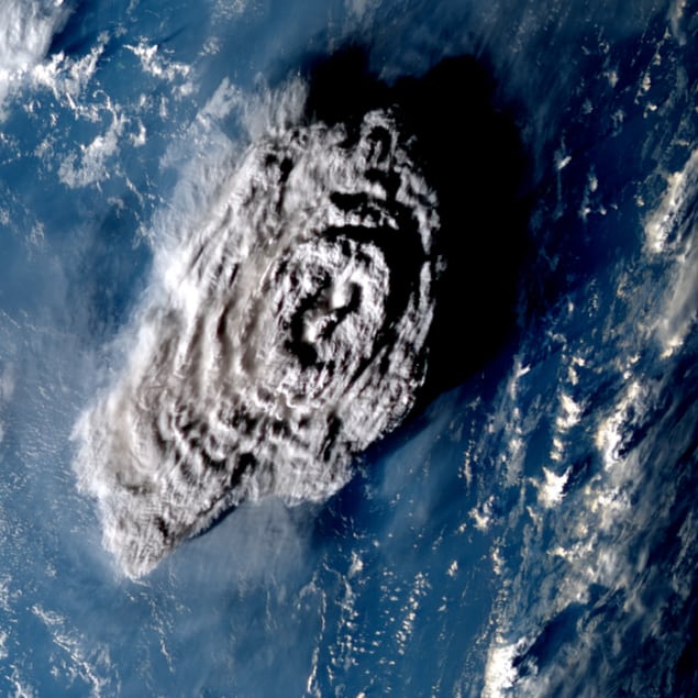Tonga 100 min after eruption. A zoomed-in view of the eruption of the Hunga Tonga-Hunga Ha’apai volcano, taken from above and showing a grey plume mushrooming towards the viewer against a background of dark blue ocean