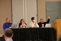 Photograph of Bill Thigpen, Jennifer Ott, Chyree Batton and Mark Fernandez, sitting behind a table during the panel discussion. Fernandez is making a thumbs-up sign