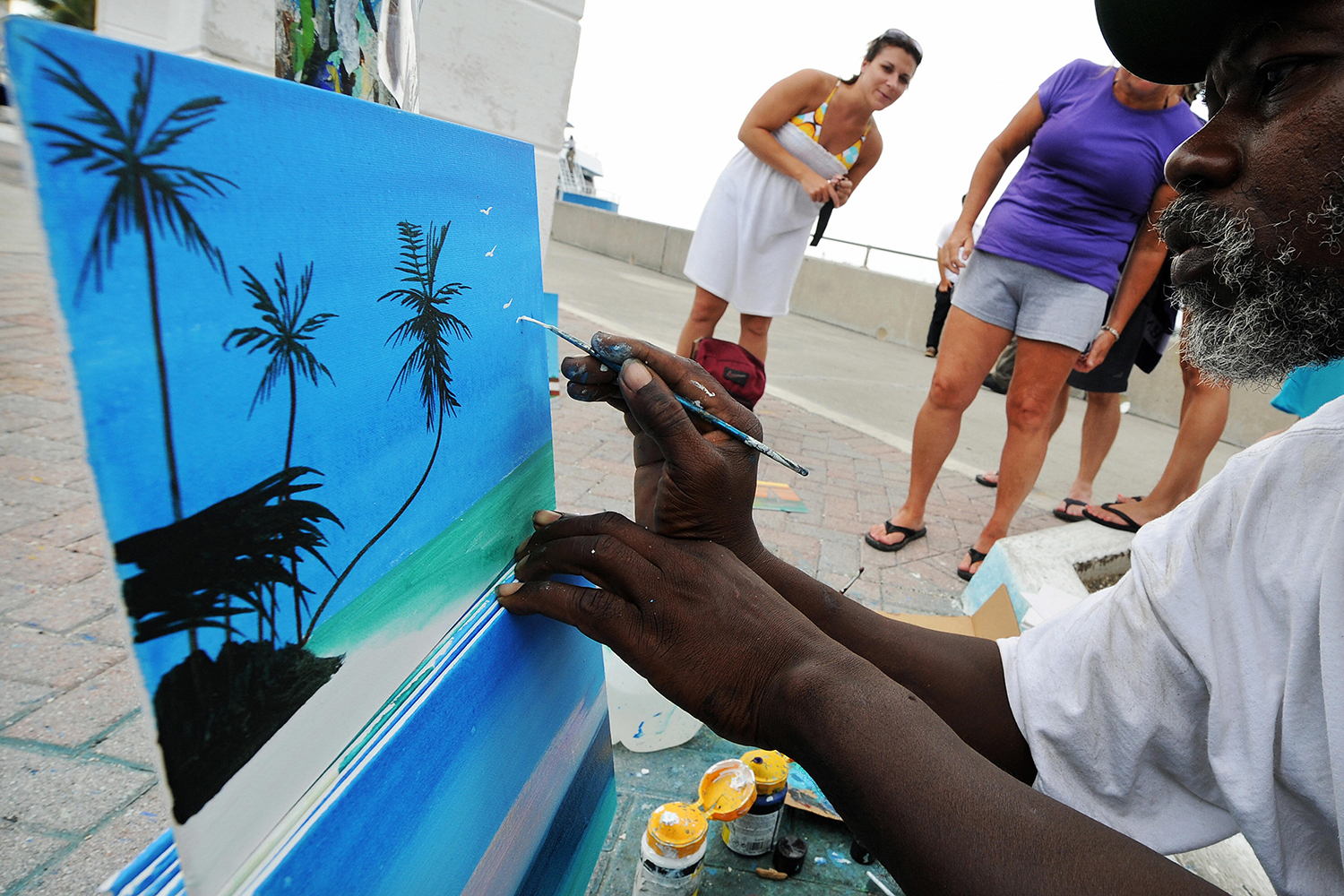 Street painter Jeff Lewis works on a painting to sell to tourists at the port in Nassau