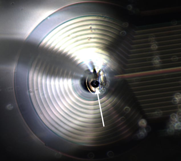 Photo of the 48-um-diameter sphere of superconducting material, which resembles a tiny ball bearing that is levitating above a chip with wires in it