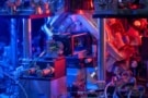 Photo of a vacuum chamber, optical fibres and other components, bathed in blue and red light