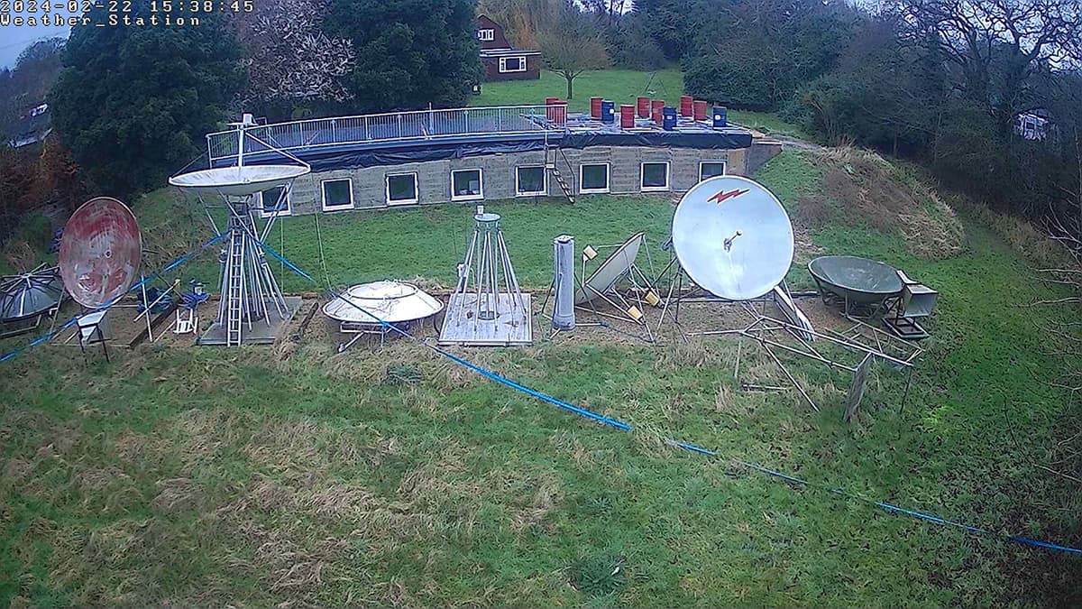 Rangée de plusieurs antennes télescopiques sur une pelouse devant un bâtiment bas en pierre