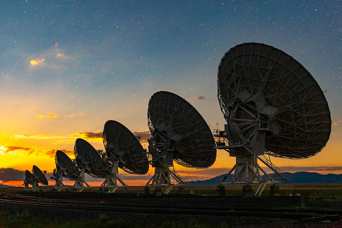 Rangée de grands radiotélescopes au coucher du soleil