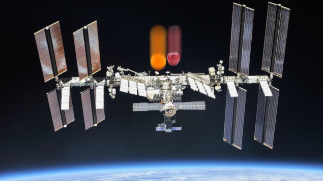 תמונה של תחנת החלל הבינלאומית במסלול סביב כדור הארץ, עם תפוח נופל ותפוז מעליו