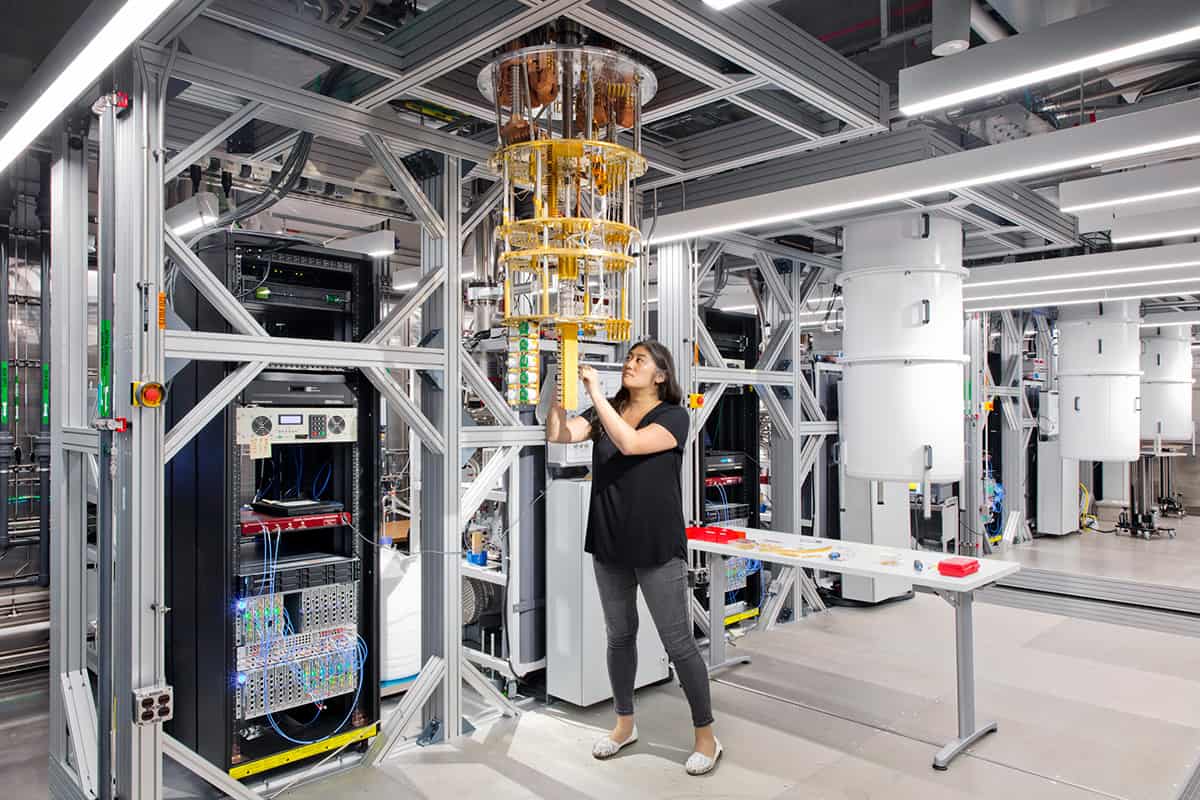 Un laboratoire informatique avec un ordinateur quantique suspendu à un cadre métallique et un scientifique ajustant quelque chose à sa base