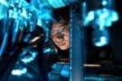 Фотография человека, использующего микроскоп, залитого синим светом.